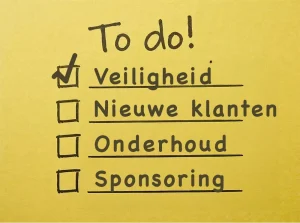 Een geeltje met daarop de tekst: 'To do!" en de punten 'Veiligheid', 'Nieuwe klanten', 'Onderhoud' en 'sponsoring'. Het punt Veiligheid staat bovenaan en is afgevinkt.